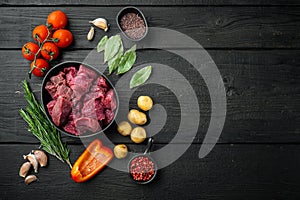 Raw lean stewing beef and potatoe, on black wooden background, top view flat lay, with copy space for text