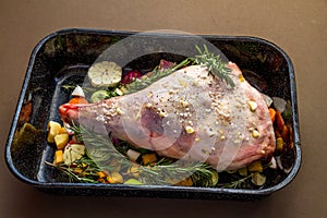 Raw Leg of lamb in roasting tray dressed with vegetables