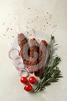 Raw lula kebab, herbs and spices on white textured background