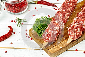 Raw lula kebab on skewers with spices on wooden board