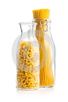 Raw macaroni pasta in glass bottle. Uncooked rigatoni isolated on white background