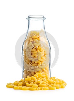 Raw macaroni pasta in glass bottle. Uncooked rigatoni isolated on white background