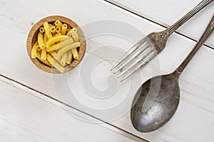 Raw macaroni pasta on grey wood