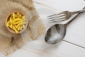 Raw macaroni pasta on grey wood