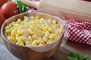Raw macaroni pasta in wooden bowl