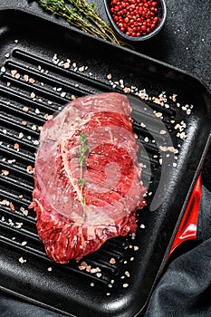 Raw marbled beef steak on a grill pan. Black background. Top view