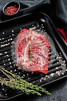 Raw marbled beef steak on a grill pan. Black background. Top view