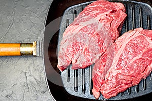 A raw marbled beef steak sits in a frying pan