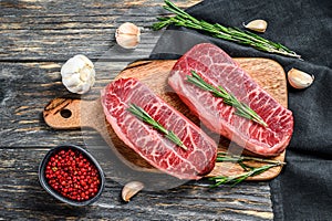 Raw marbled beef steak, top blade meat steak. Black background. Top view