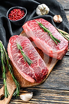 Raw marbled beef steak, top blade meat steak. Black background. Top view