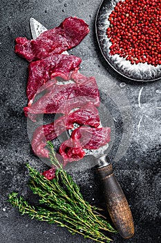 Raw marbled meat cut into thin strips for beefstroganoff. Black background. Top view