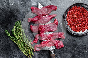 Raw marbled meat cut into thin strips for beefstroganoff. Black background. Top view