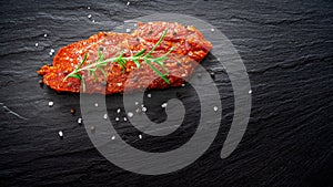 Raw marinated meat, beef steak on black slate background, top view