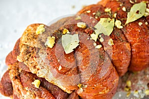 Raw marinated pork roll sprinkled with spices and tied with string. Lying on foil.