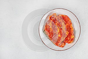 Raw marinated pork steaks with spices and herbs on white plate. top view. copy space