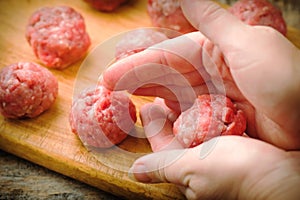 Raw meat balls on a chopping board.