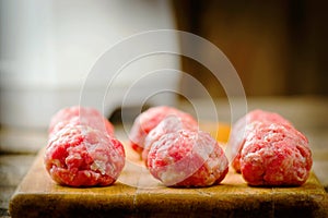 Raw meat balls on a chopping board.