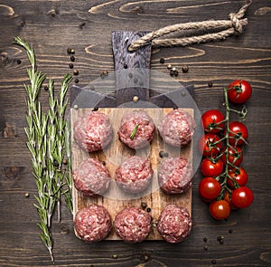 Raw meat balls with vegetables, butter and herbs on wooden rustic background top view close up