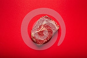 Raw meat beef prime cut steak Ribeye on clean red background from above, beefsteak concept banner minimalism