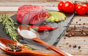Raw meat, beef with spices for cooking on black board