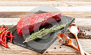 Raw meat, beef with spices for cooking on black board