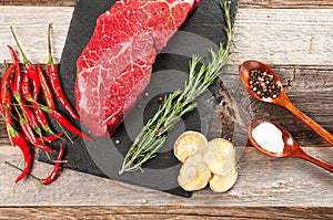 Raw meat, beef with spices for cooking on black board