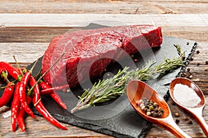 Raw meat, beef with spices for cooking on black board