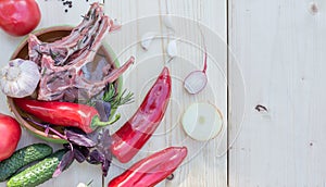 Raw meat on a bone prepared for frying, in a bowl with fresh paprika, garlic and herbs, copy space