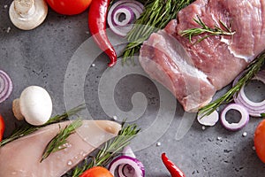 Raw meat, chicken fillet, pork tenderloin with spices, rosemary,  pepper, onion, mushrooms on a gray background top view