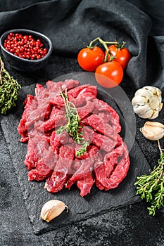 Raw meat cut into thin strips for beef Stroganoff. Black background. Top view