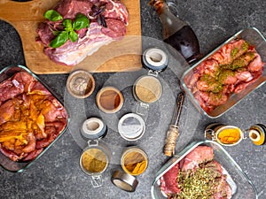 Raw meat in different marinades as soy sauce, pomegranate sauce, spices and herbs in a glass bowls