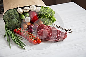 Raw meat, different vegetables and fruits on white wooden table.