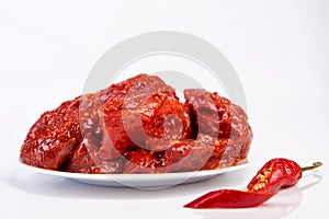 Raw meat marinated in spicy sauce close-up, isolated on white background with slices pepper