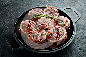 Raw meat medallions wrapped in bacon. in a pan, ready to cook. On a concrete background.