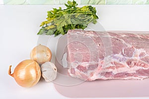 Raw meat, onion and garlic and a bunch of parsley on the kitchen table.