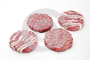 Raw meat patties for burgers on a white background.