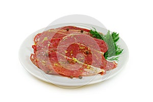 Raw meat. Pork escalope slices with sause in a Dish Isolated Against White Background