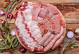 Raw meat products.Barbecue pork ribs, steaks, grilled sausages,minced meat, garnished with spices on a round wooden chopping board