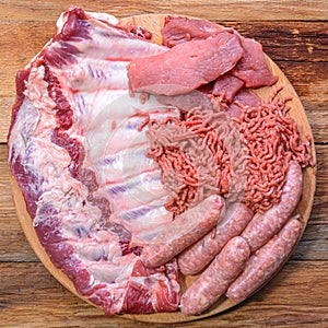 Raw meat products.Barbecue pork ribs, steaks, grilled sausages,minced meat, garnished with spices on a round wooden chopping board