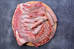 Raw meat products.Barbecue pork ribs, steaks, grilled sausages,minced meat, garnished with spices on a round wooden chopping board