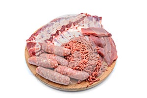 Raw meat products. pork ribs, neck steaks, homemade sausages, minced meat garnished with spices, on a round wooden chopping board.