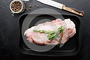 Raw meat roll a piece before baking with rosemary, allspice. With coarse sea salt on a black baking sheet. Home simple