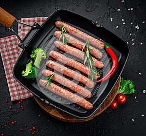 Raw meat sausages on a square grill pan, with herbs and spices