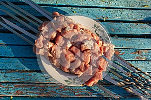 Raw meat skewers on a plate on rustic blue wooden background before grilling