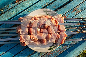 Raw meat skewers on a plate on rustic blue wooden background before grilling