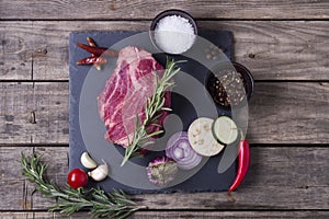 Raw meat steak from marble beef with vegetables on the stone plate. Top view