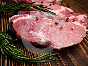 Raw meat, steak on a wooden Board. Spices, garlic, rosemary, peppers. Ready for cooking and roasting.