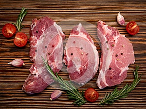 Raw meat, steak on a wooden Board. Spices, garlic, rosemary, peppers, tomato. Ready for cooking and roasting.