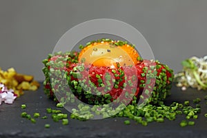 Raw meat tartare steak and egg yolk on black board