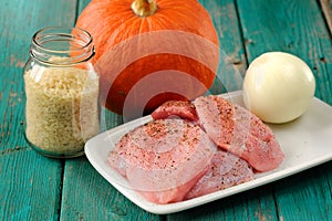 Raw meat, whole pumpkin, onion and rice with pepper mill